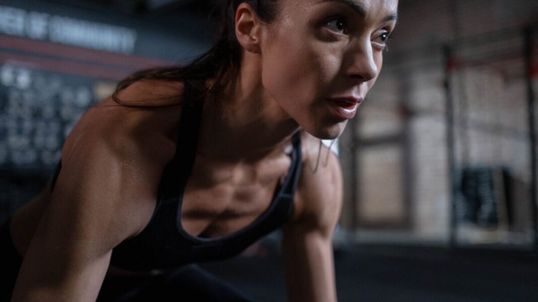 Close-up of a determined female athlete sweating during a workout session indoors.