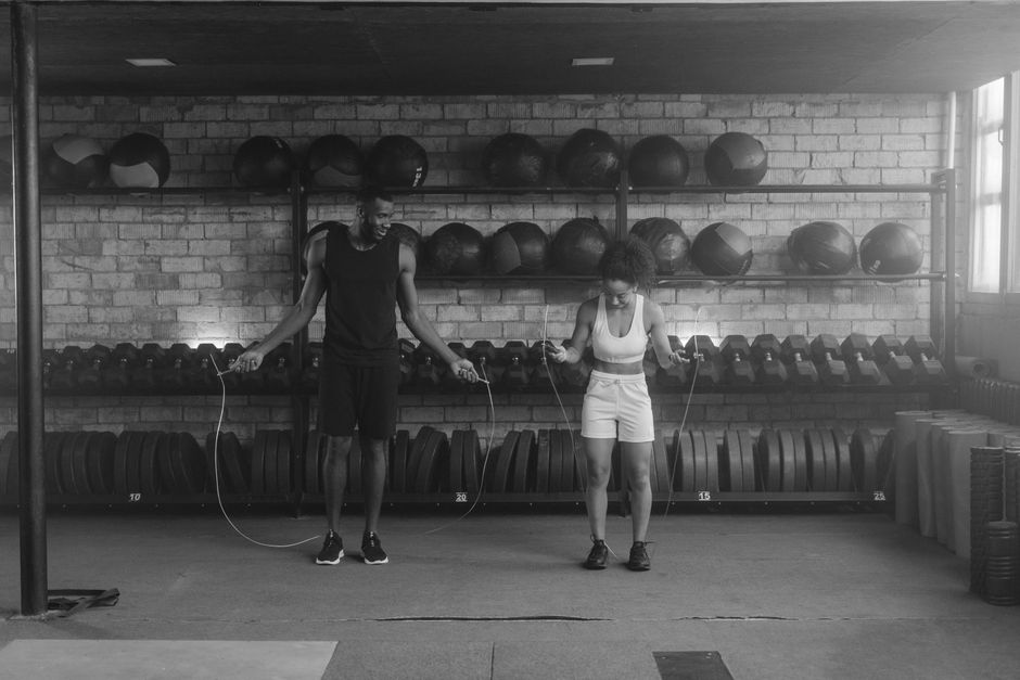 A fit couple working out in the gym with jump ropes, promoting a healthy lifestyle.